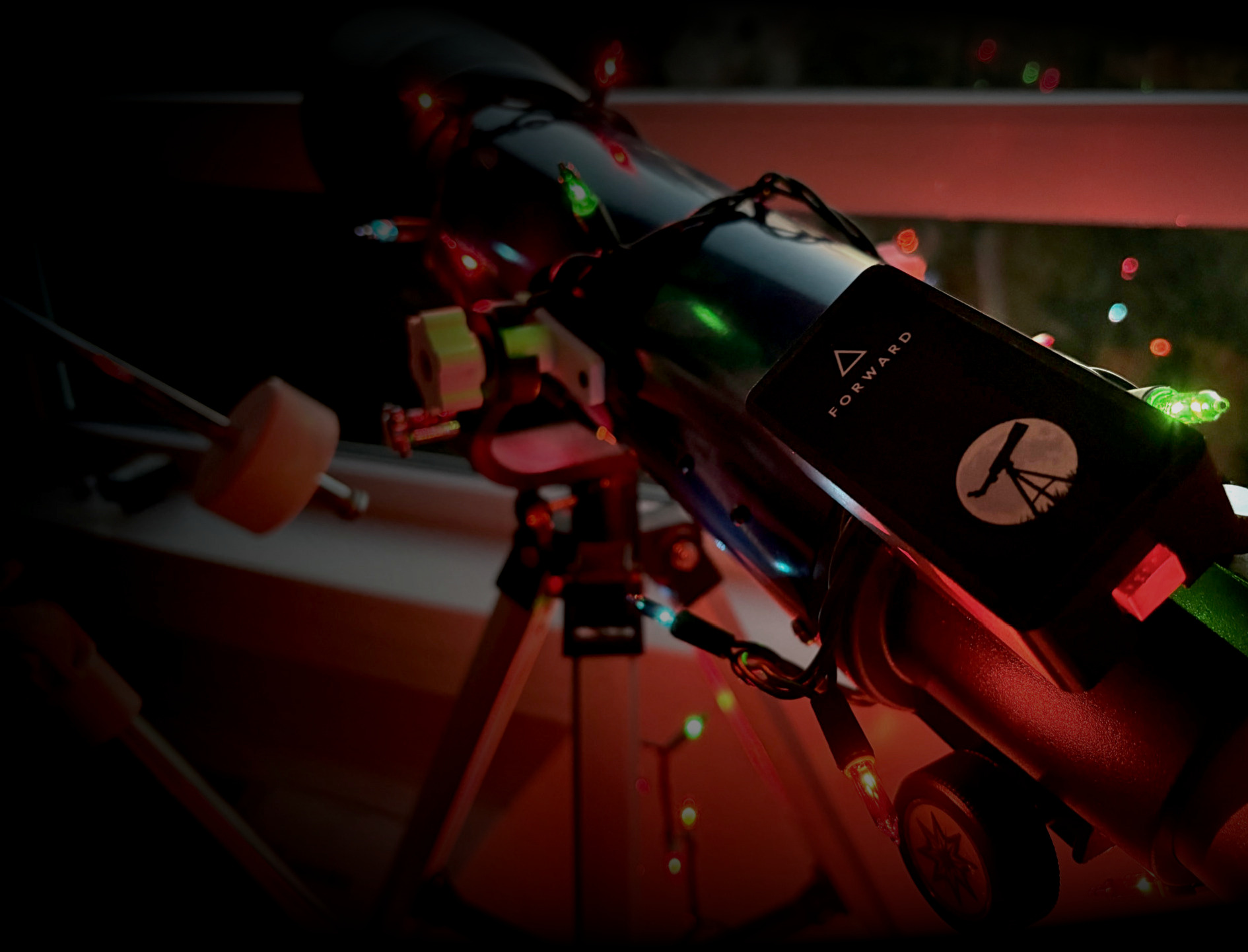 A picture of a mobile phone held next to a telescope. Stargraph is mounted 
               to the telescope with it's distinctive red power button shining brightly.
               On the app is a targeting system, currently zeroed out.